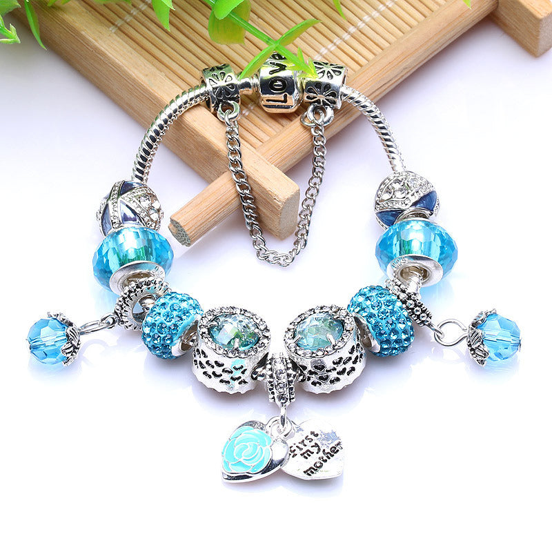 Silver charm bracelet with blue bead charms, heart tag and love script pendant