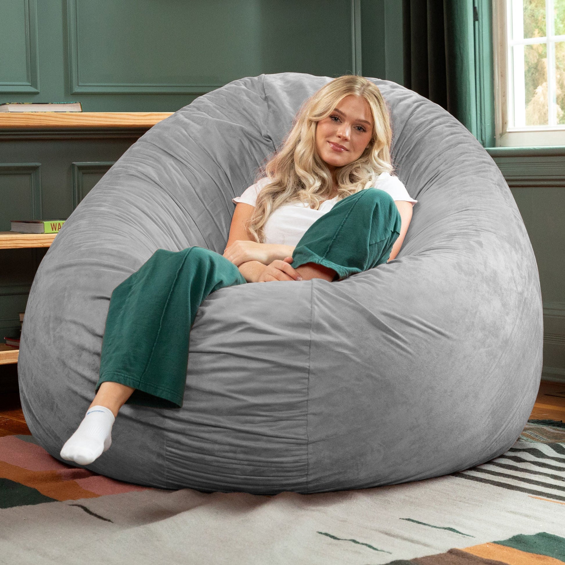 Large bean bag chair, gray cocoon backrest with woman reclining and legs up