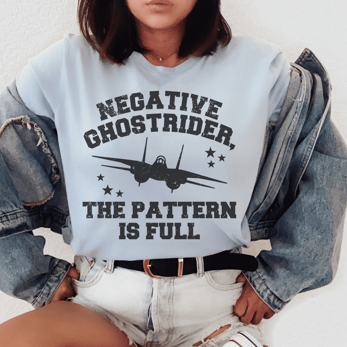 Light blue graphic airplane T-shirt worn by woman, front text print visible