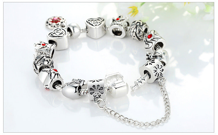 Silver charm bracelet with red enamel flower charms and silver bead caps, linked chain