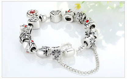 Silver charm bracelet with red enamel flower charms and silver bead caps, linked chain