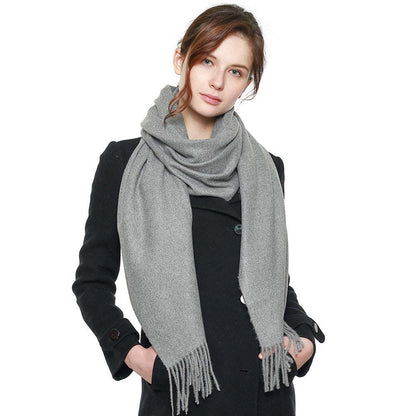 Gray pashmina shawl with fringe trim, loosely wrapped around neck
