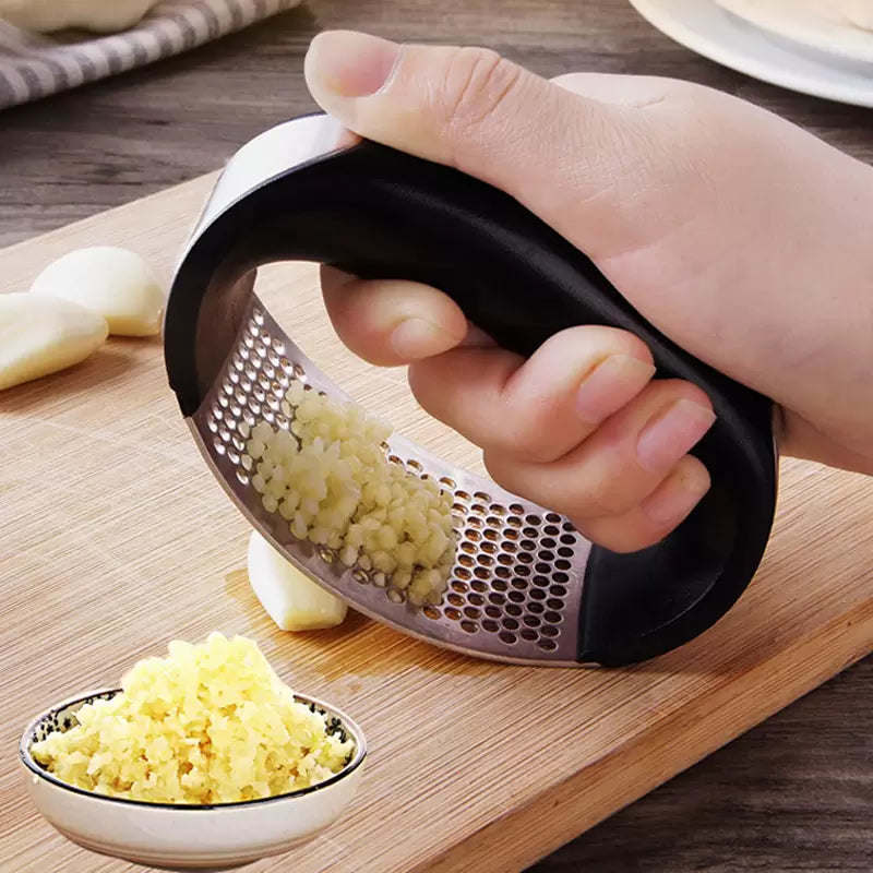 Hand crushing garlic with a stainless steel garlic press, black handle and perforated plate