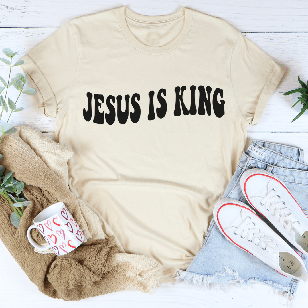 Cream short-sleeve T-shirt with black "JESUS IS KING" front graphic.
