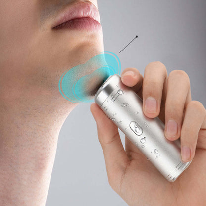 Silver mini USB shaver held against skin, with blue glow for shaving area