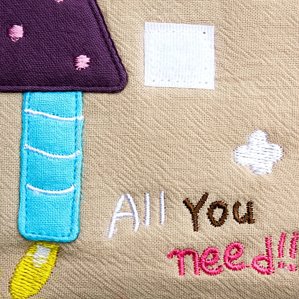 Embroidered fabric wallet close-up, purple and blue applique over tan with text