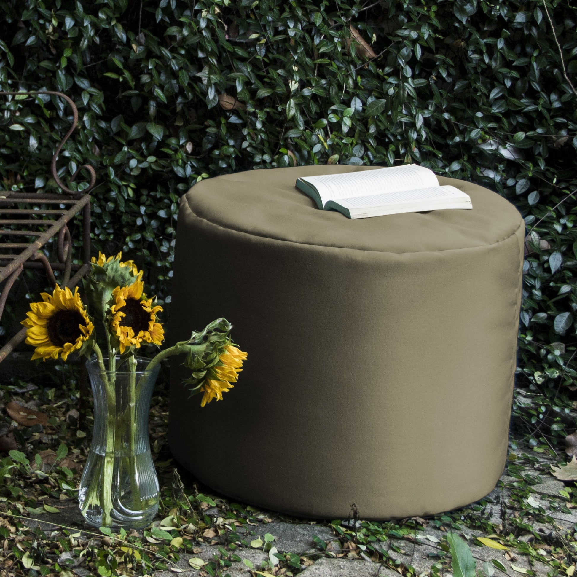 Taupe round outdoor ottoman with book resting on padded top