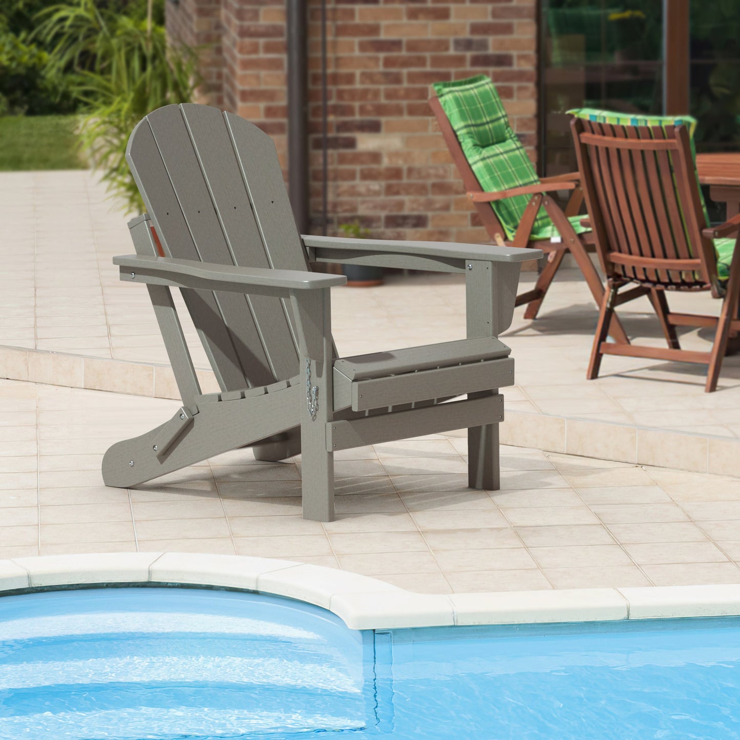 Folding Adirondack-style patio chair with wide arms and curved back, placed on tiled patio.