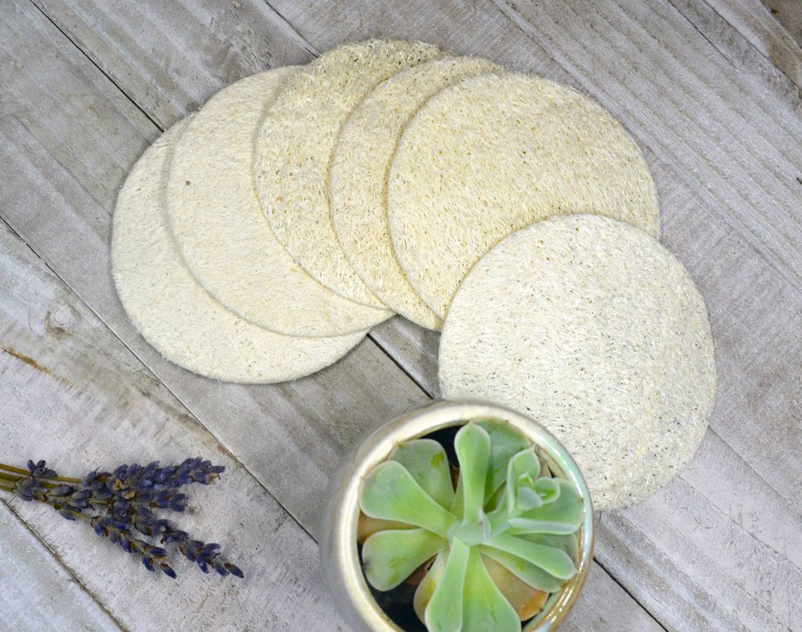 Loofah sponge pads, round beige discs laid out with a small bowl nearby.