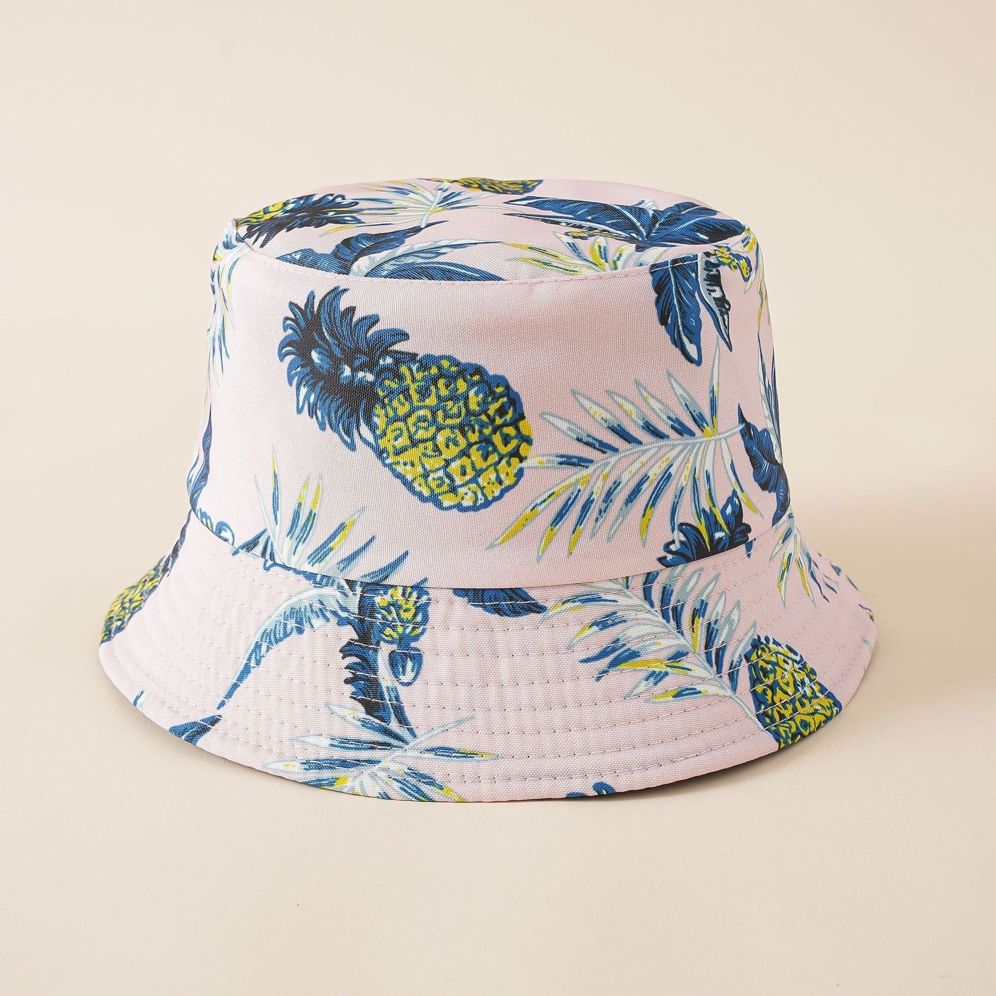 Cream fisherman bucket hat with blue pineapple and palm leaf print, wide brim
