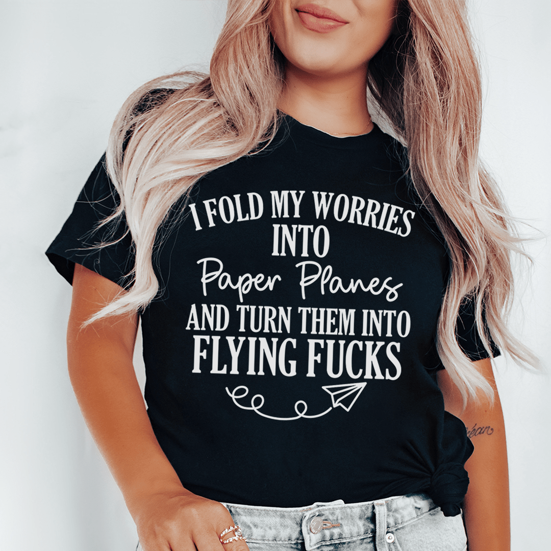 Model wearing black T-shirt with front text graphic about folding worries into paper planes