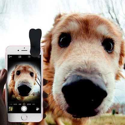 Smartphone with clip-on camera lens attachment showing a pet photo on screen