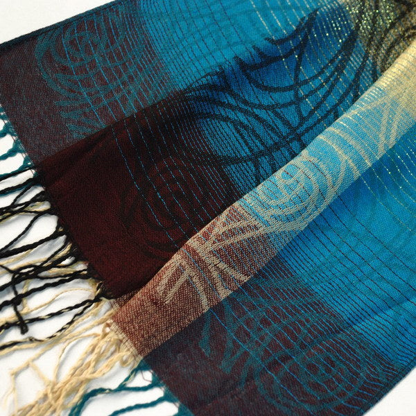 Close-up of pashmina shawl fabric with teal, blue, burgundy, and beige woven pattern