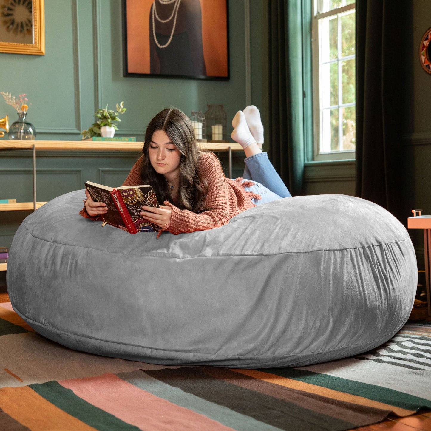 Large bean bag chair in gray, rounded seat with person reading while seated