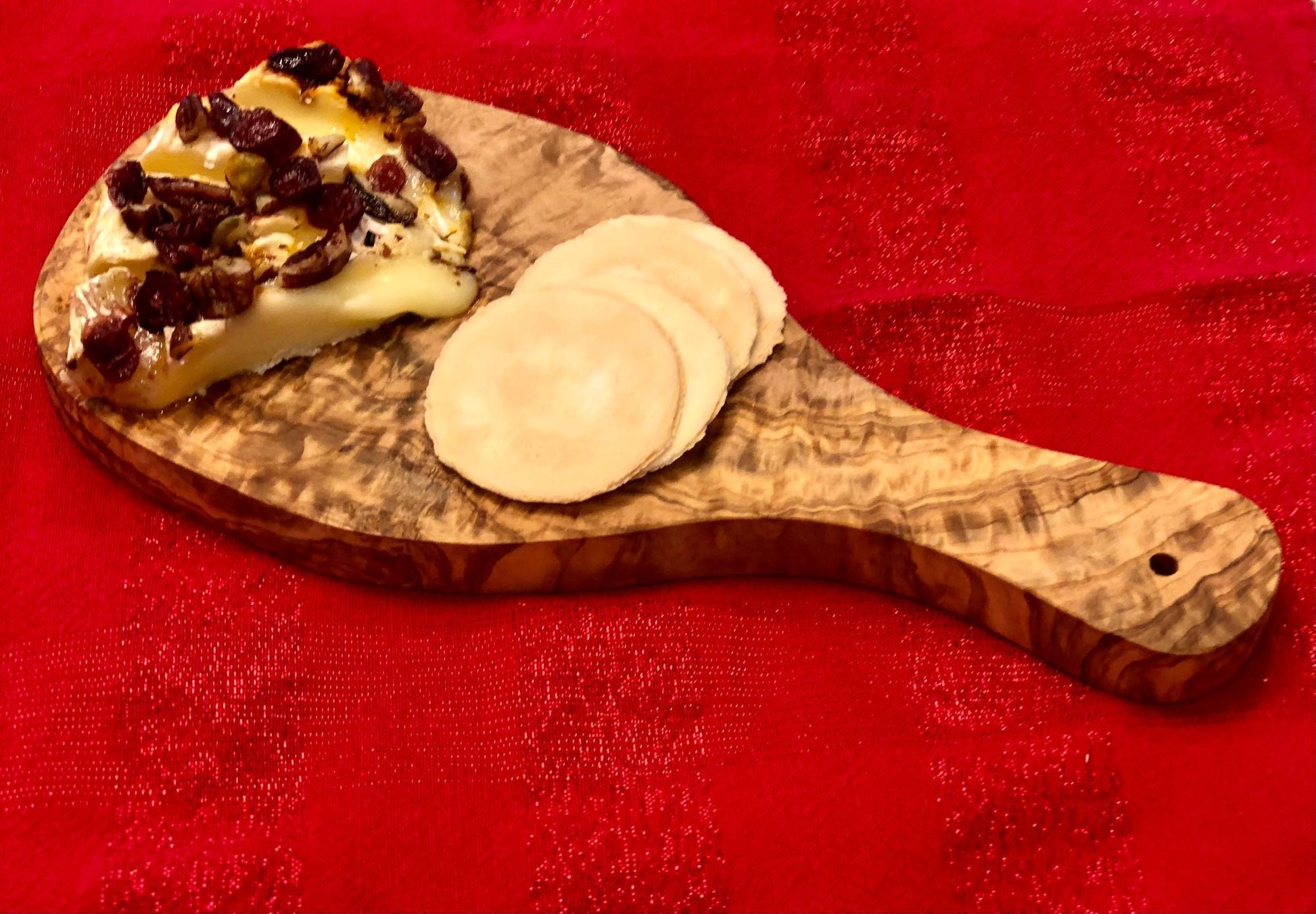 Olive-wood cutting board with handle, bread slice and cheese rounds