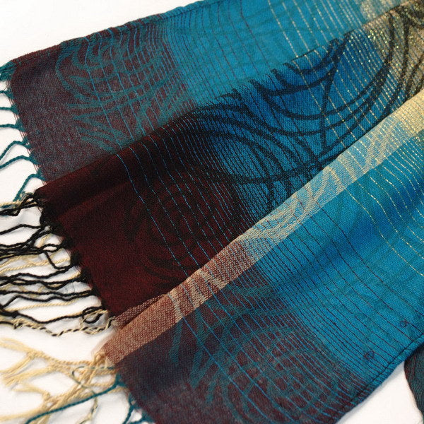 Close-up of patterned pashmina fabric in teal, blue, and dark maroon with gold trim