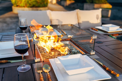 Rectangular firepit table with open flames and dining placemats on wooden surface