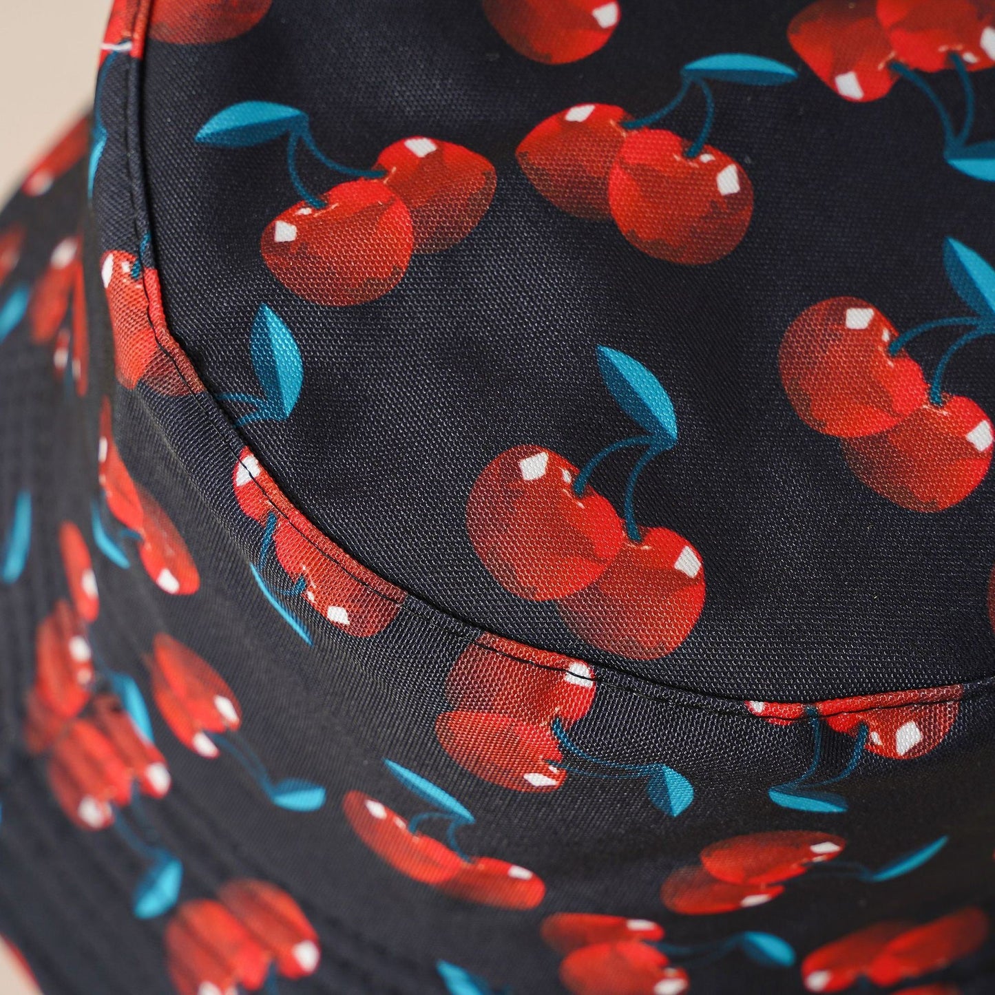 Double-sided cherry bucket hat close-up, dark brim with red cherries and blue leaves
