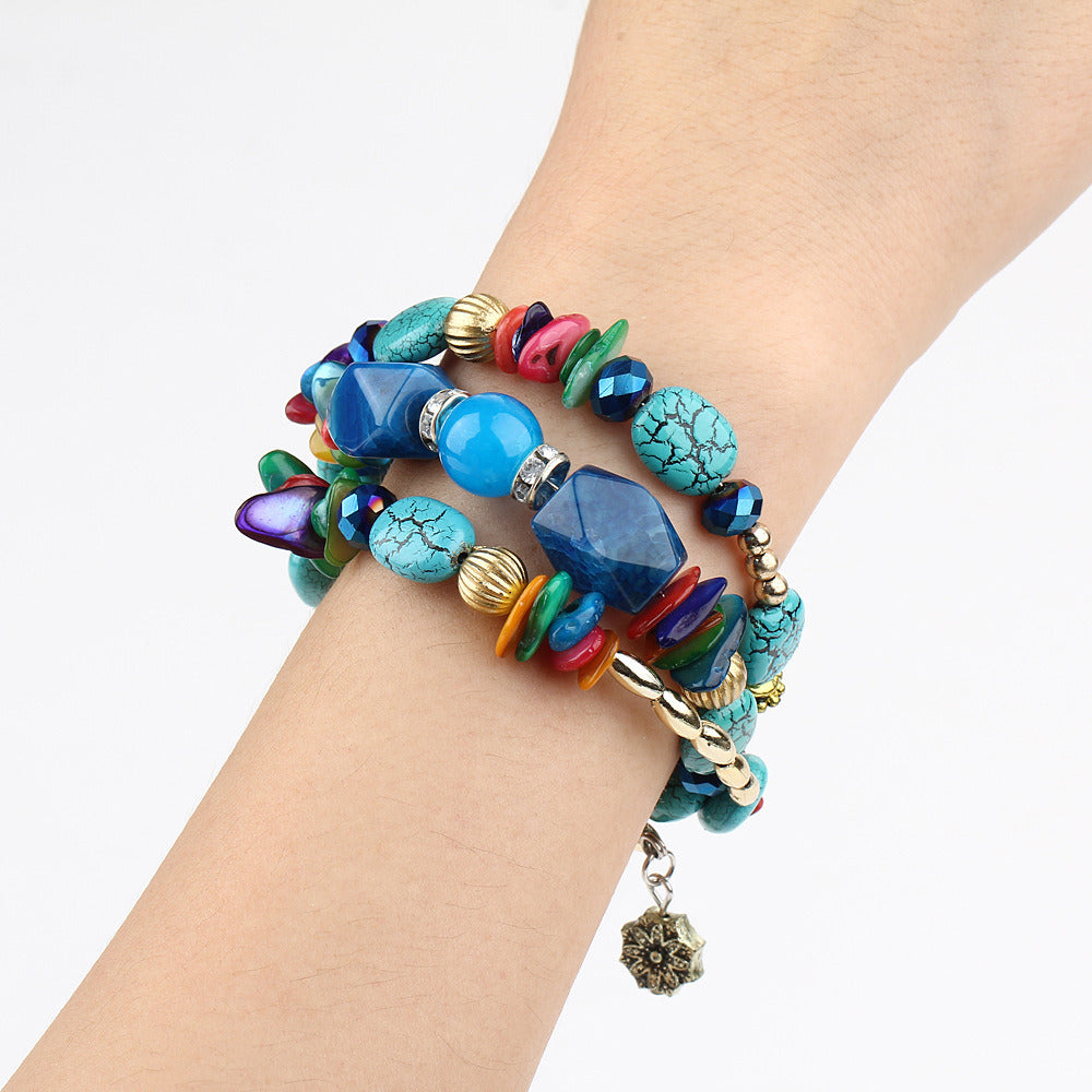 Multilayer boho charm bracelet on wrist with blue turquoise beads and colorful details