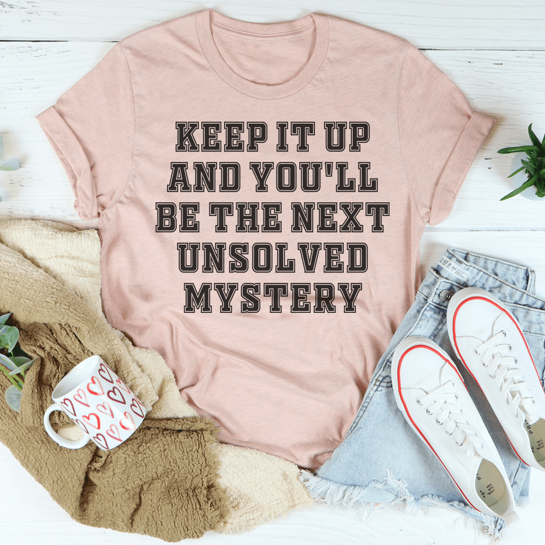 Heather pink crewneck t-shirt with large "KEEP IT UP" and "UNSOLVED MYSTERY" text graphic
