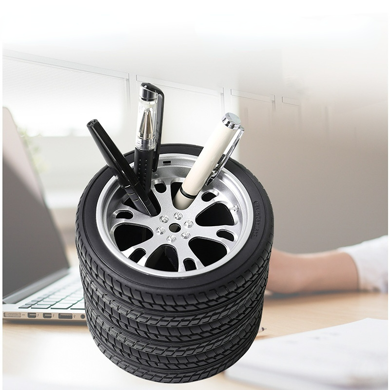 Black wheel-shaped tire pen holder holding pens on a desktop