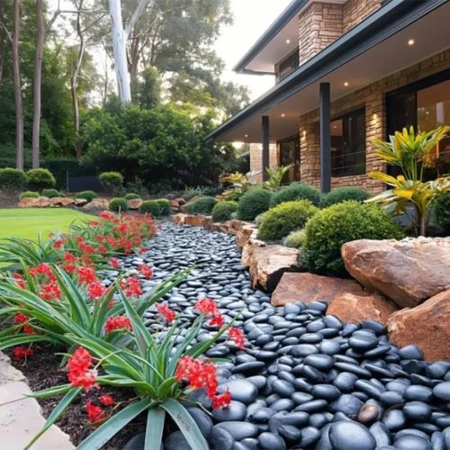 Polished black river rock pathway with small smooth pebbles and flower garden border