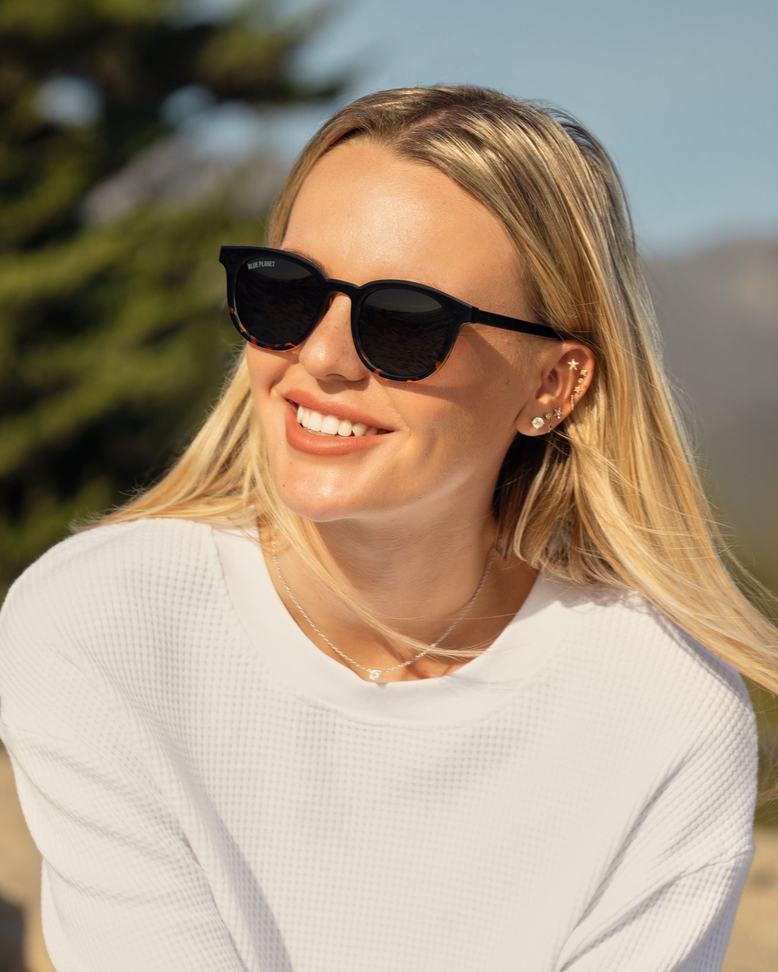 Black polarized sunglasses on a person with blonde hair and oval brown lenses