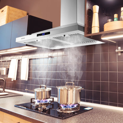 Stainless steel wall range hood over a gas cooktop on a dark backsplash