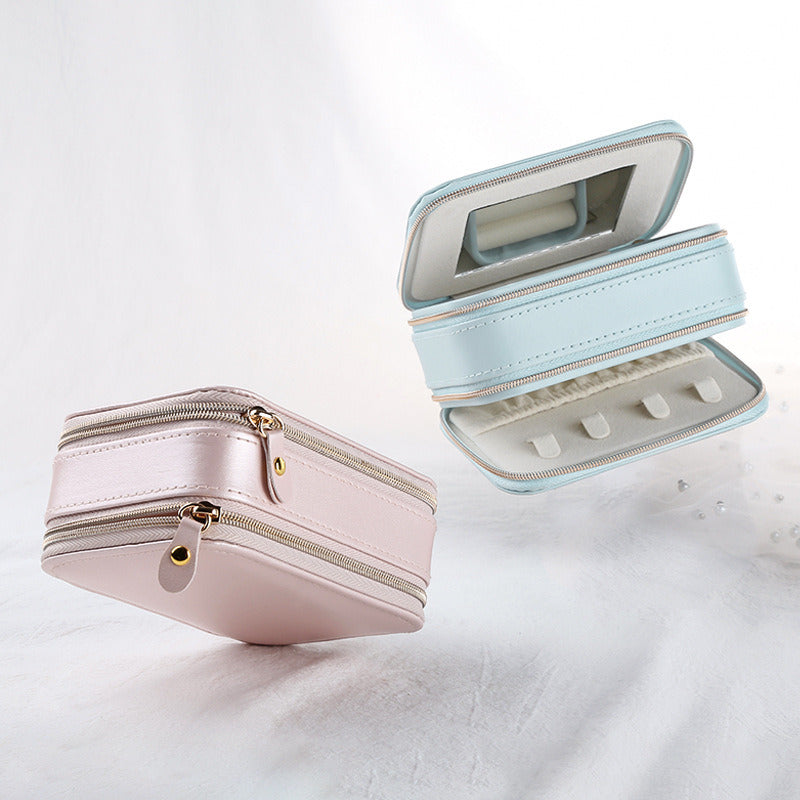 Light blue PU jewelry case open with built-in mirror and ring slots; pink case closed