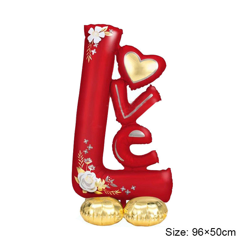 Standing foil balloon decoration in red with heart and love-style lettering on golden base balloons.