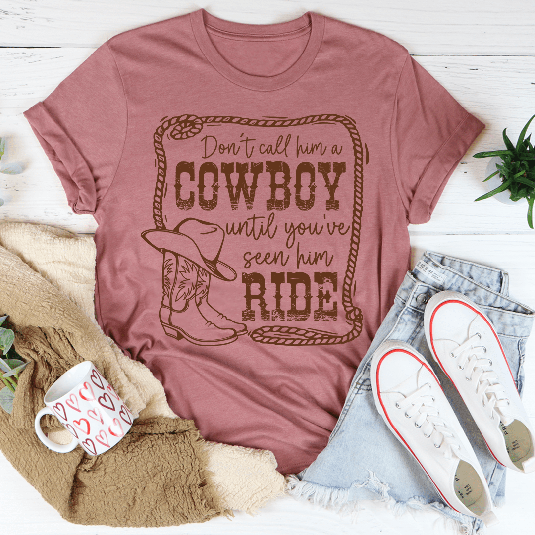 Dusty pink crewneck cowboy slogan t-shirt with centered western graphic: Don't call him a Cowboy until you've seen him ride