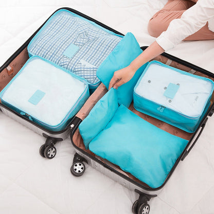 Turquoise packing cubes with mesh panels and zipper closures in an open suitcase