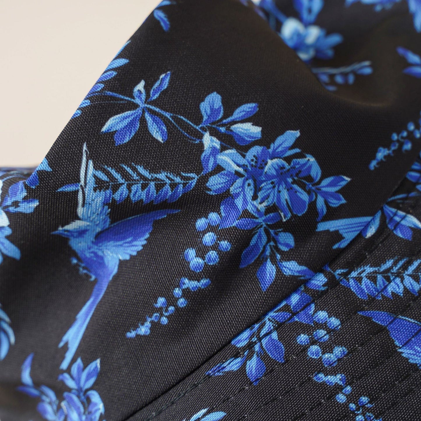 Black hat fabric close-up with bright blue flower and leaf pattern
