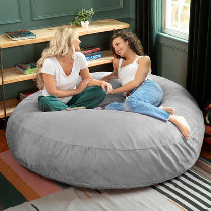 Large bean bag chair in gray cocoon form, two people relaxing on the seat