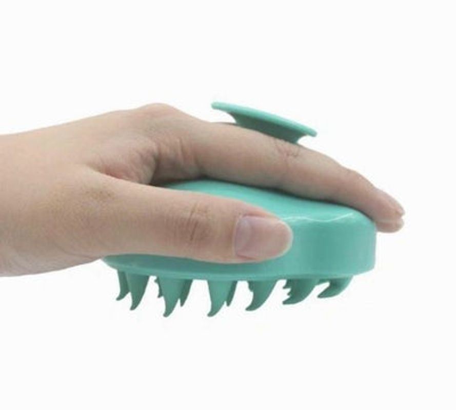Teal silicone scalp massager brush shown from side, spike bristles on underside