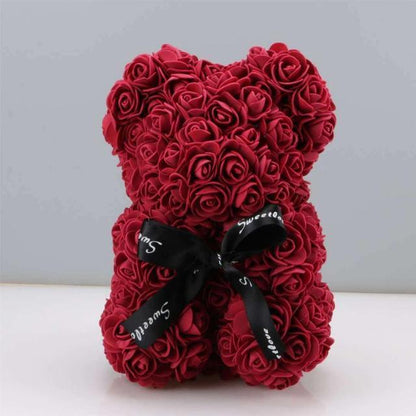 Red rose teddy bear with layered rose petals and a black ribbon bow at the chest