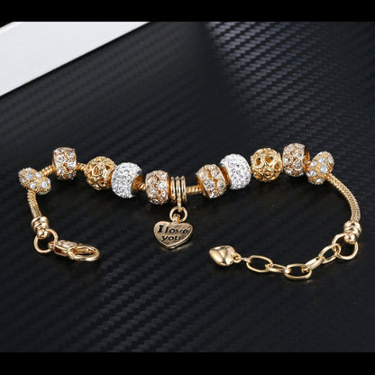 Gold plated bead bracelet with alternating crystal and amber-toned charms and heart pendant
