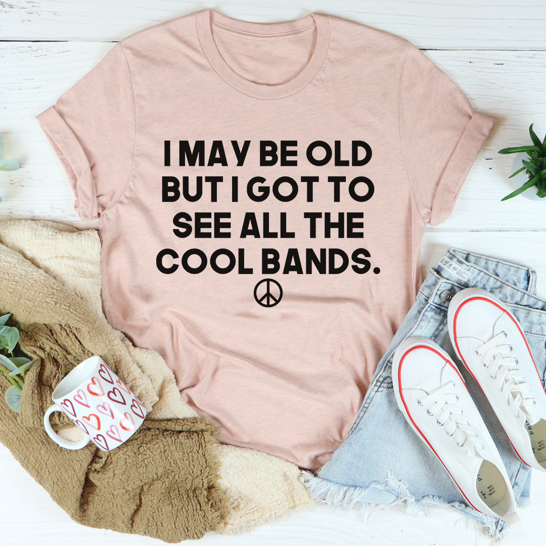 Light pink crewneck T-shirt with bold black 'I MAY BE OLD' slogan and peace symbol