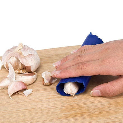 Garlic press crushing garlic cloves on a wooden cutting board.