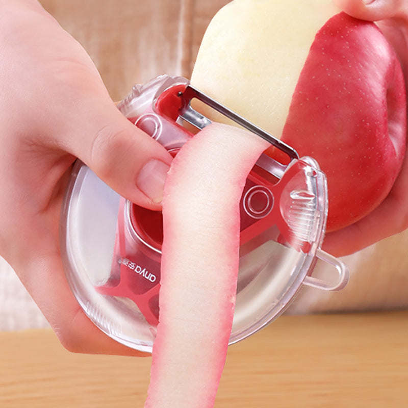 Vegetable and fruit peeler with clear guard and red blade, held over peeled produce
