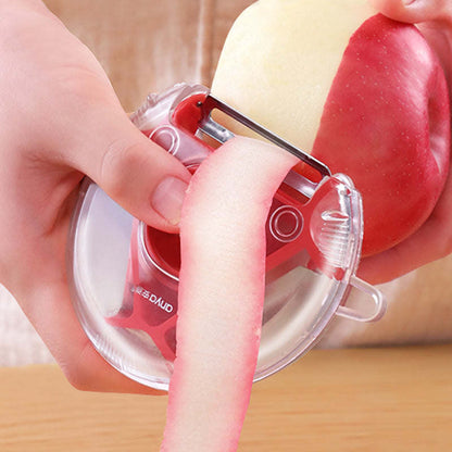 Vegetable and fruit peeler with clear guard and red blade, held over peeled produce