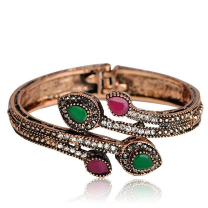 Rose-gold tone bypass bangle with green and magenta oval stones and clear CZ accents