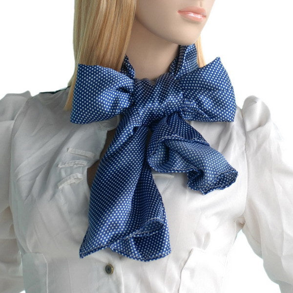 Dark blue silk scarf with white dots tied in a bow at the neck
