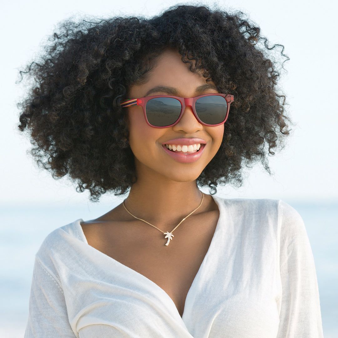 Red bifocal sunglasses with dark lenses on a woman with curly hair