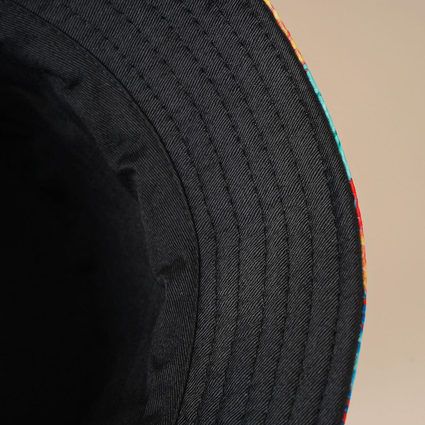 Dark fisherman hat close-up with ribbed stitch texture and teal piping