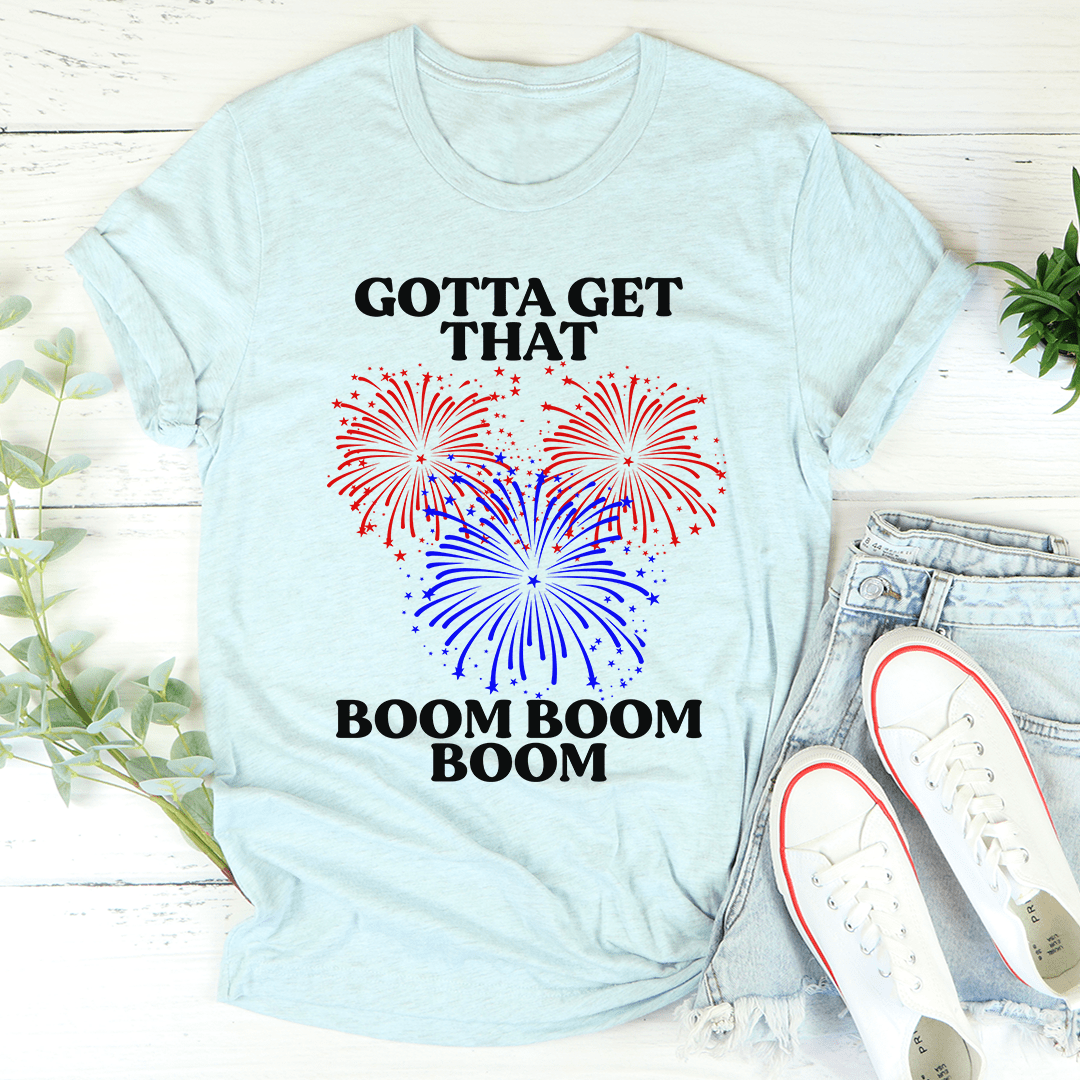 Light blue crewneck T-shirt with centered fireworks graphic and 'BOOM BOOM BOOM' text