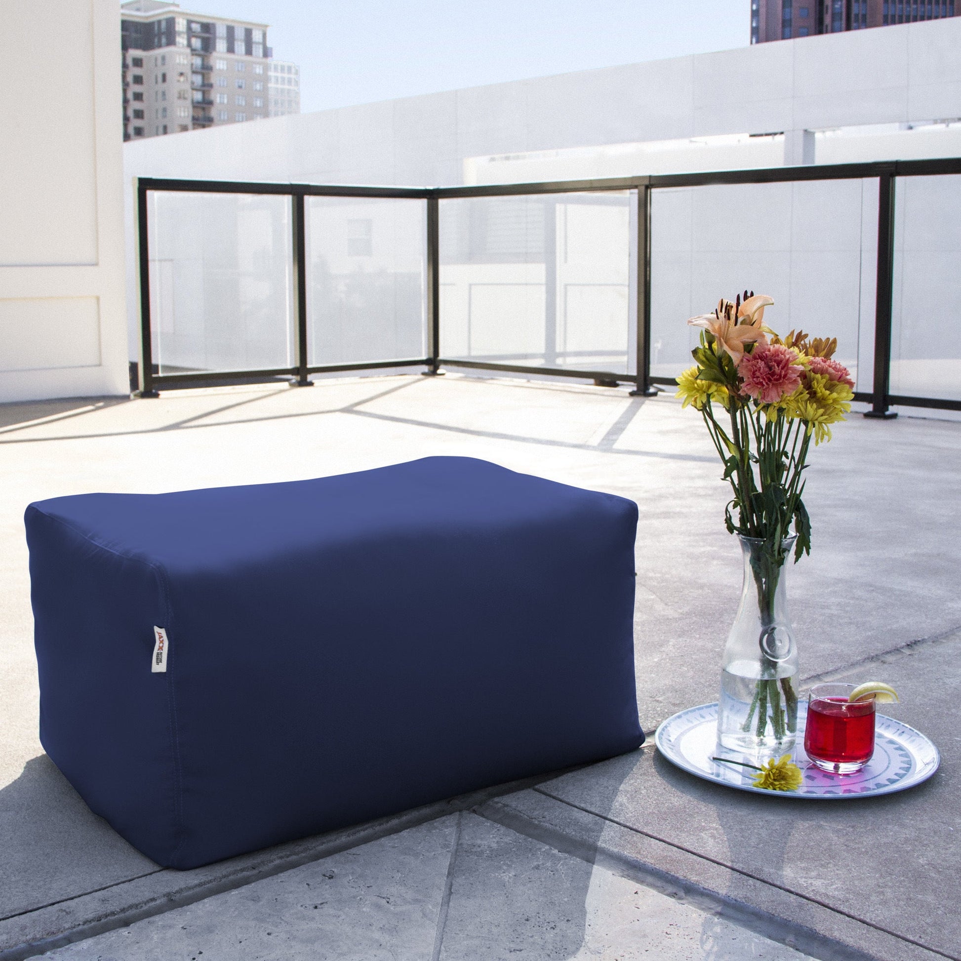 Navy bean bag ottoman, low boxy shape with stitched seams on the sides.
