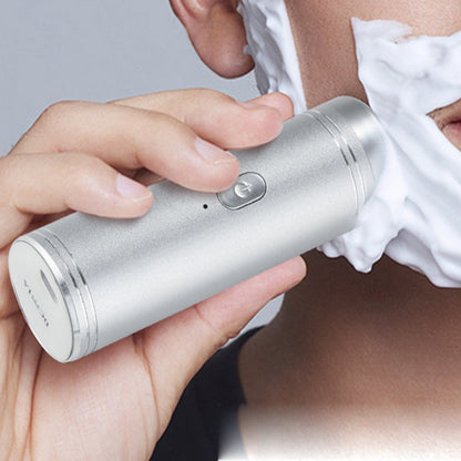 Silver mini USB shaver with circular head, held in hand during use on skin