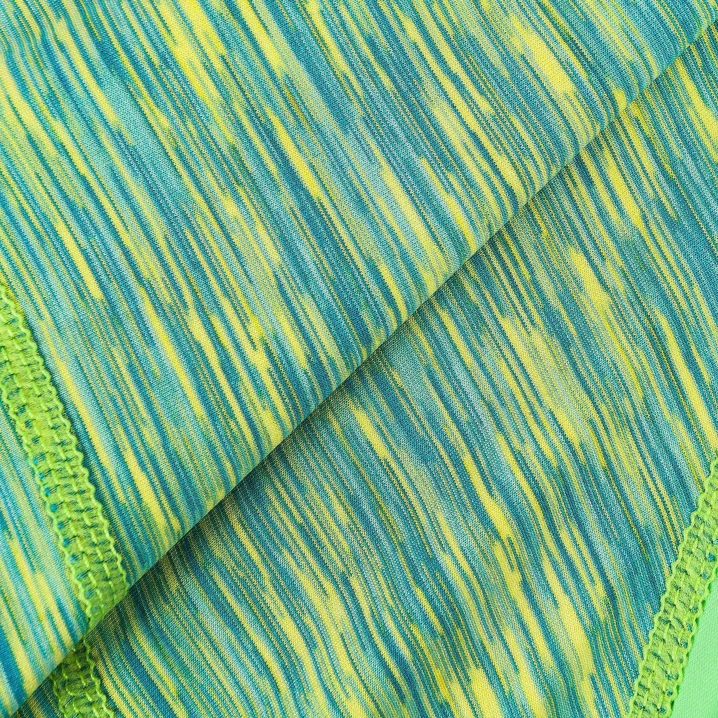 Close-up of green-and-blue heathered fabric with knit texture and stitched seam