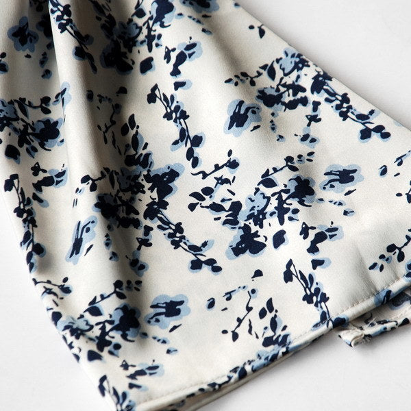 Close-up of white silk scarf fabric with scattered dark blue floral sprigs